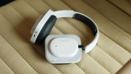 Nothing Headphones (a) folded on cream leather seat